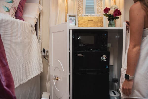 A nightstand opening to reveal a microwave and mini fridge inside