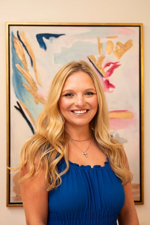 Interior designer standing in a decorated dorm room in front of a custom painting.